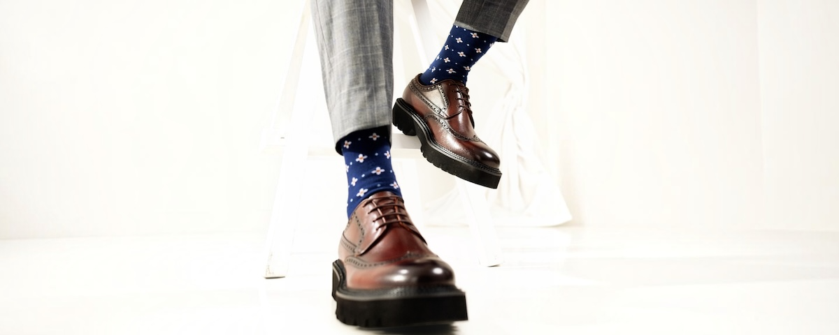 A pair of hand-lasted black oxford shoes on a light backdrop